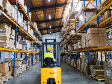 Warehouse worker standing near safety light curtains ensuring compliance with OSHA and ANSI standards for machinery safety and personnel protection