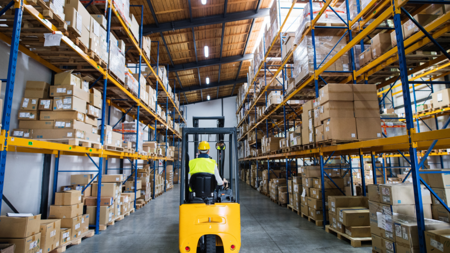 Warehouse worker standing near safety light curtains ensuring compliance with OSHA and ANSI standards for machinery safety and personnel protection