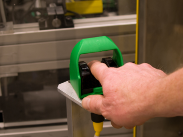 Operator using an ergonomic palm button in an industrial setting, demonstrating safe two-hand control for machinery operation.