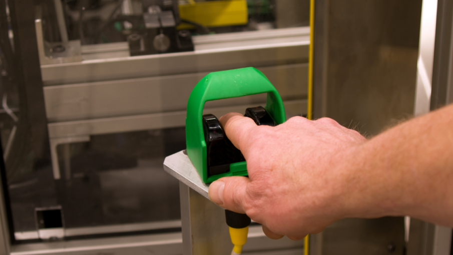 Operator using an ergonomic palm button in an industrial setting, demonstrating safe two-hand control for machinery operation.