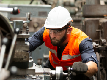 Worker in a machine shop wearing safety gear, demonstrating the use of safety sensors like light curtains and mats to prevent accidents and enhance industrial safety.