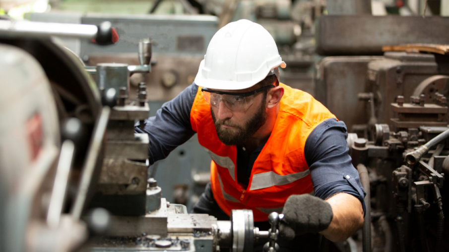 Worker in a machine shop wearing safety gear, demonstrating the use of safety sensors like light curtains and mats to prevent accidents and enhance industrial safety.