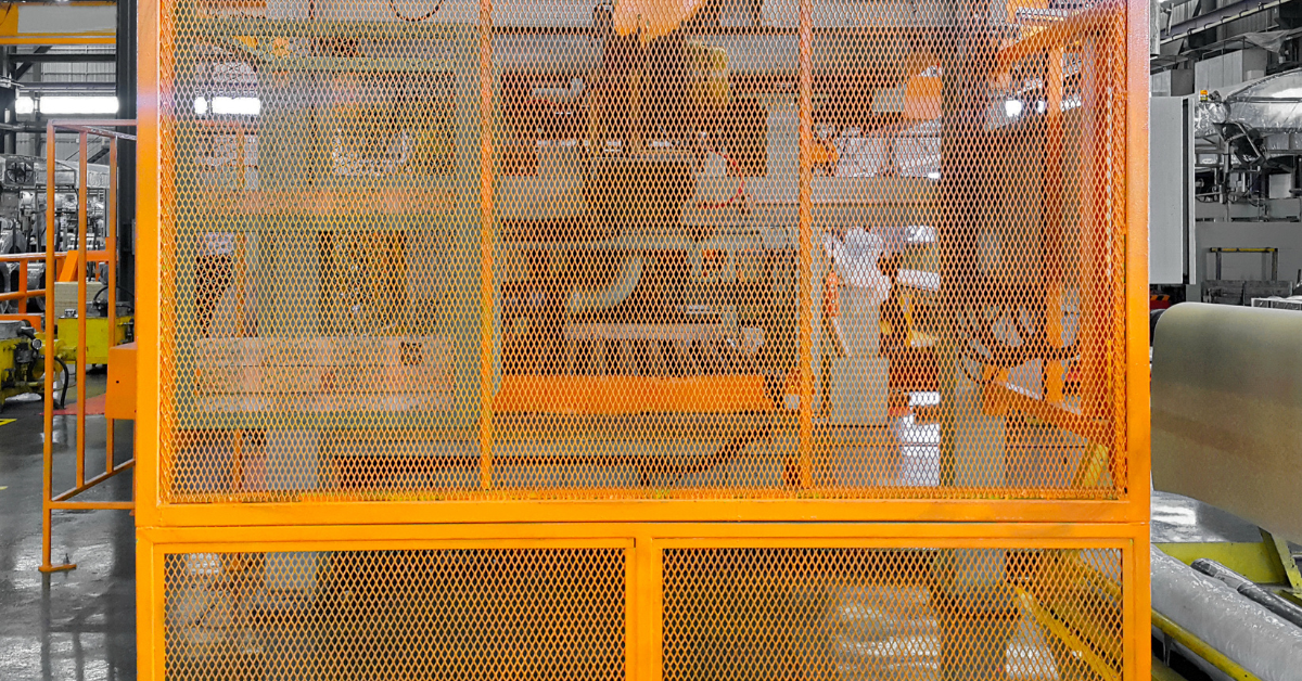 Plant floor with orange safety fencing highlighting appropriate fence heights to secure machinery and protect workers in hazardous zones.