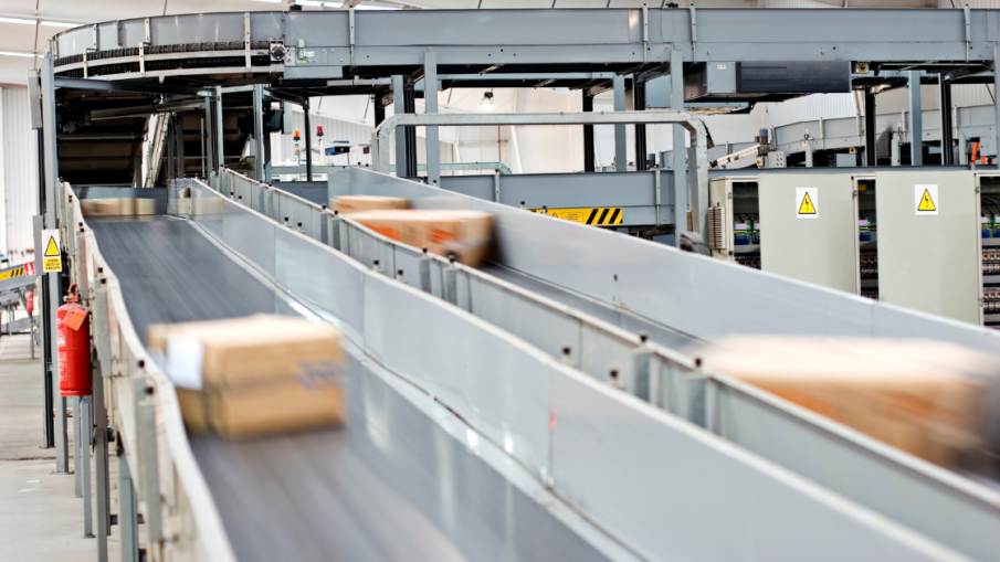 Industrial conveyor belt system transporting materials, equipped with proper machine guarding for worker safety and compliance with safety regulations.